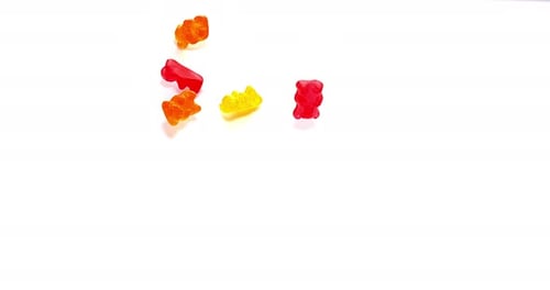 Colorful Gummy Bears Falling onto a White Surface