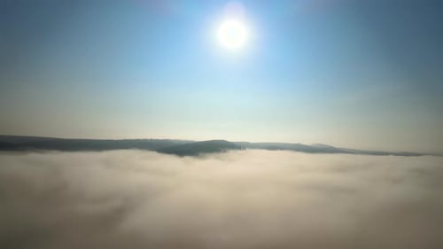 Aerial View of Colorful Sunrise Over White Dense Fog with Distant Dark Silhouettes of Mountain Hills
