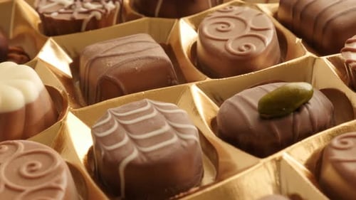 Box of chocolates many different candies slow tilt 4K 2160p 30fps UltraHD footage - Tilting over ass