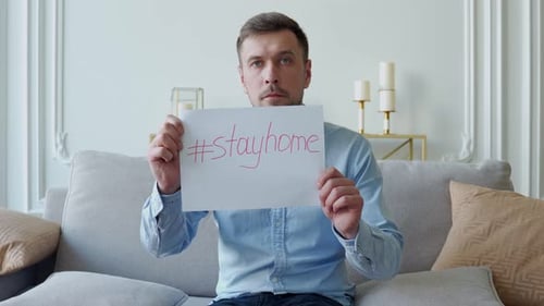 Adult Man Holding Stay Home Sign on Couch