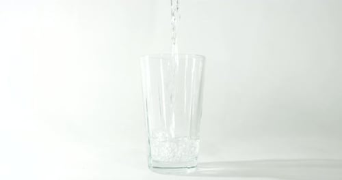 Imágenes a cámara lenta de un vaso de agua rellenado contra un fondo limpio y claro