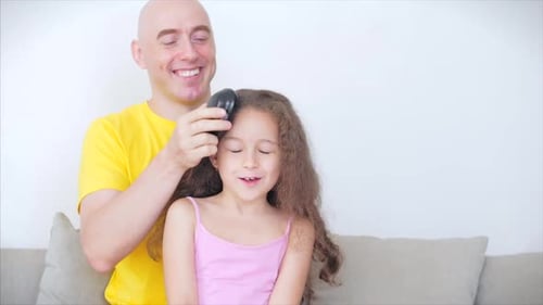 Loving Father Brushing Young Daughter's Curly Hair
