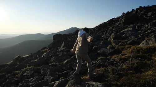 A Tourist Girl in Hiking Shoes Climbs Up Walking in the Mountainous Area