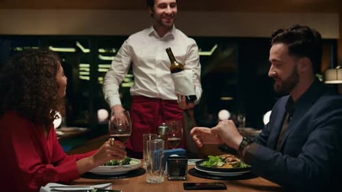 Sommelier Waiter Pour Wine to Romantic Couple in Restaurant