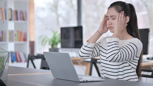 Laptop Use By Young Asian Woman with Headache in Office