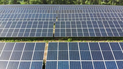 Luftaufnahme des Solarkraftwerks. Paneele stehen in einer Reihe auf der grünen Wiese.
Sommer