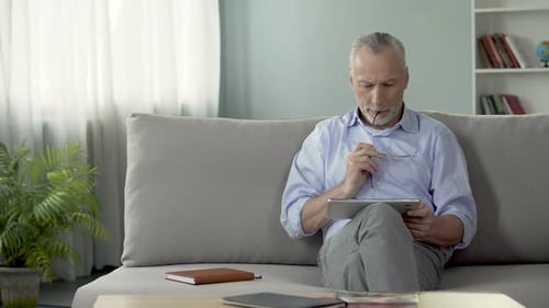 Senior Man Relaxing at Home Using Tablet