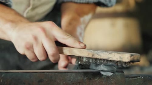 Ein Schmied mit einer Metallbürste reinigt das Werkstück von Kalk und Schmutz