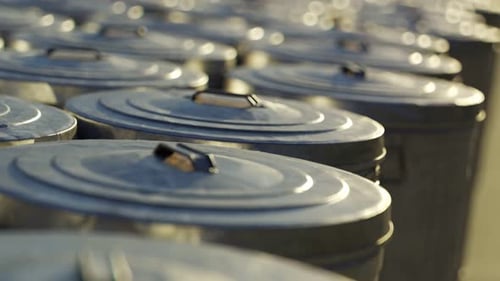Steel trash bins stacked together in an endless loop lit by the sunlight. 4KHD