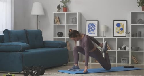 Woman Stretching Leg on Yoga Mat Indoors
