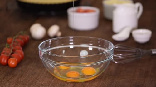 Batir tres huevos de gallina crudos frescos en un tazón de vidrio