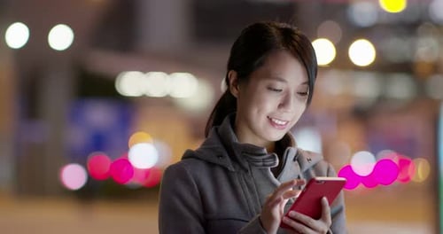 Asian woman use of mobile phone in city at night
