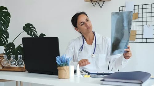 Female Doctor Looking at X-ray in Office