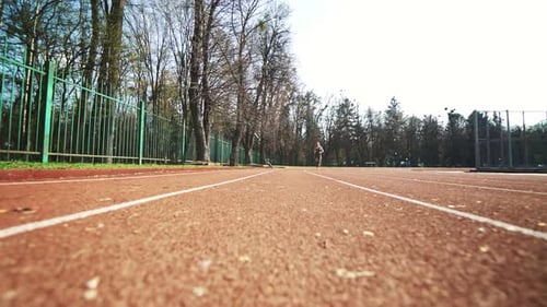 Athletic Woman Running on a Track Outside
