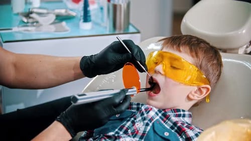 A Little Boy in Protective Glasses Having His Teeth Done - Putting the Photopolymer Lamp in the