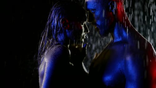 Sensual Couple Embracing Under Red and Blue Rain