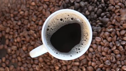 Closeup Video of a Cup of Coffee on a Big Pile of Coffee Beans