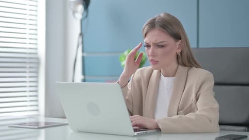 Stressed Woman Typing on Laptop in Bright Office