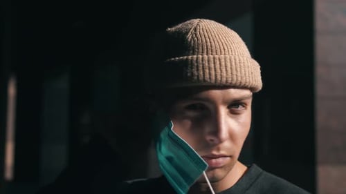 Young Adult Puts on Surgical Mask Indoors