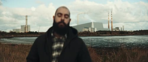 Man stands infront of lake and factory
