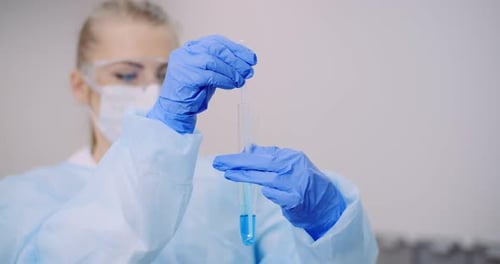 Woman Dripping Blue Liquid into Test Tube in Lab