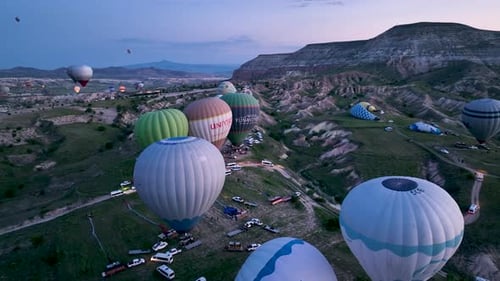 Hot air balloons fly over the mountainous landscape of Cappadocia, Turkey.