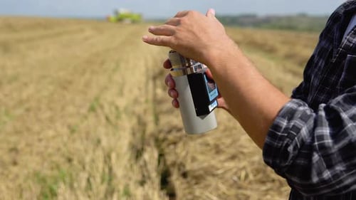 Young Farmer Inspects the State of Wheat with Special Equipment
