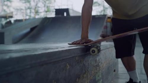 Man Hands Touching Skateboard Wheels at Skate Park