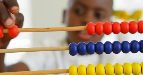 Front view of little black boy studying with abacus in a comfortable home 4k