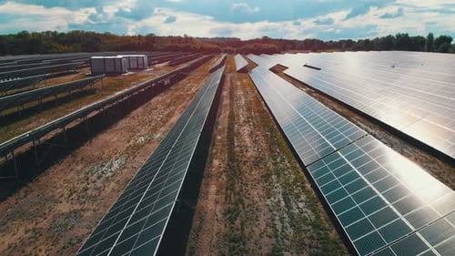 Luftaufnahme des Solarkraftwerks. Paneele stehen in einer Reihe auf der grünen Wiese.
Sommer