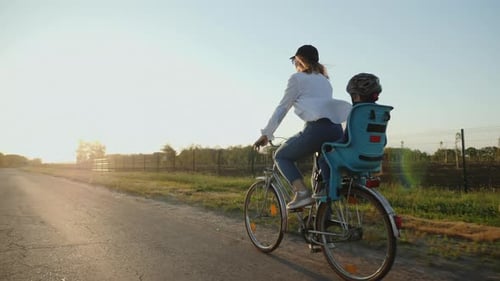 Mom with Her Little Son Are Riding a Bike
