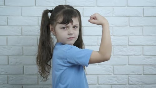 Confident Young Girl Flexing Muscle Indoors