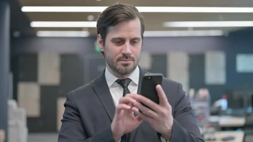 Man in Suit Using Smartphone in Office