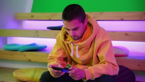 Man Focused on Handheld Game at Home