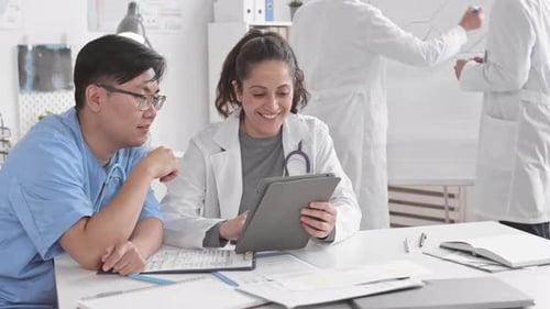 Medical Team Collaborating with Tablet in Office