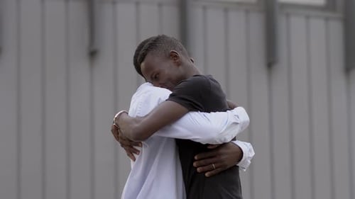 African black men greeting and hugging in the street- slow motion