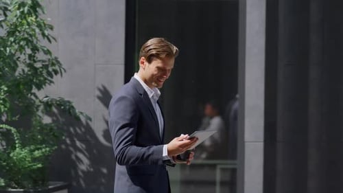 Smiling Finance Worker Checking Smartphone Walking in Modern Workplace Outside