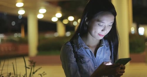 Young Woman Using Smartphone at Night in City