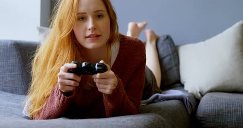 Woman Lying on Couch Playing Video Game