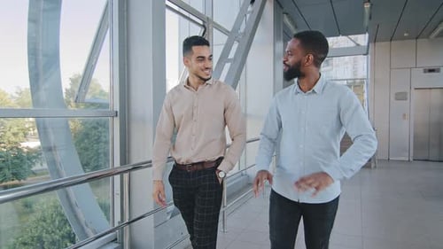 Two Young Men Walking and Talking Indoors