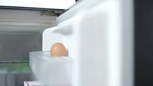 Le chef place les œufs crus du marché dans le compartiment du réfrigérateur.
