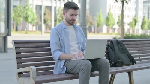 Man Working on Laptop Experiences Back Pain Outdoors
