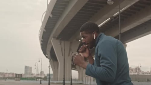Man Shadow Boxing Outdoors Under Overpass Structure