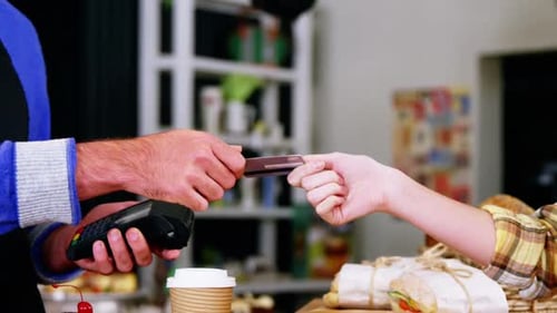 Customer making payment through payment terminal machine at counter