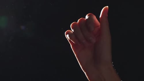 Illuminated Hand Gesturing Against Dark Background