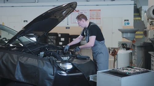 A Mechanic at a Car Service Station Checking the Battery