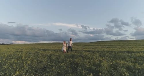 Young Couple Running Through Green Field