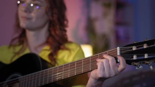 Woman Plays Guitar Skillfully Under Colorful Lights