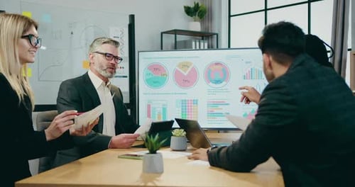 Business Team Reviews Data in Modern Office