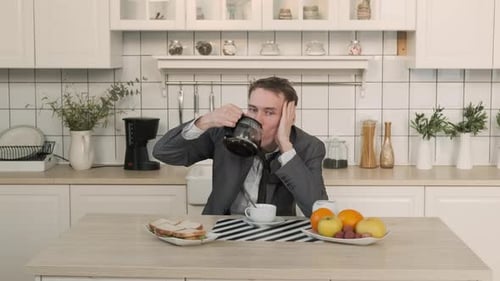 Tired Man Drinks Coffee in Kitchen